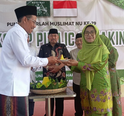 Ketua Tanfidziyah PCNU Jepara KH Charis Rohman menyerahkan potongan tumpeng ke Ketua Muslimat NU Jepara Hj Noor Ainy.